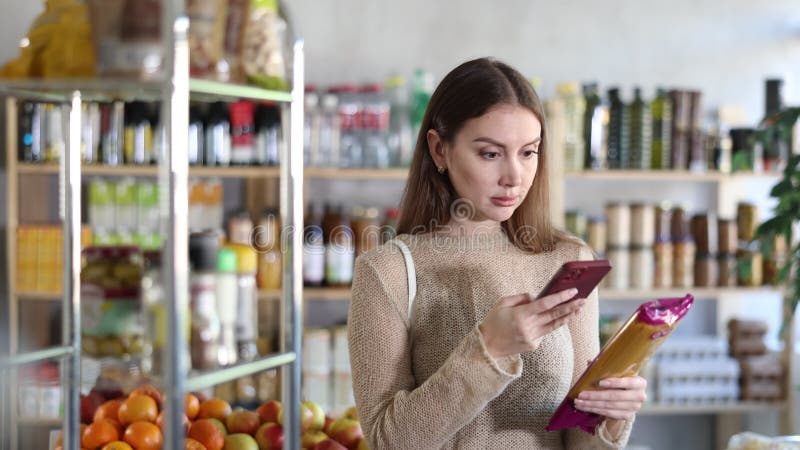 Female purchaser scanning QR code or barcode of spaghetti in supermarket stock video