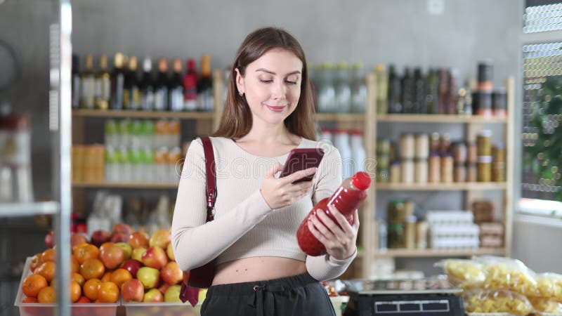 Female purchaser scanning QR code or barcode of tomato juice in supermarket stock footage