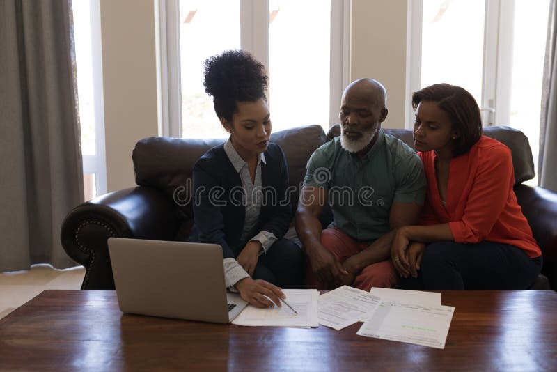 Female real estate agent and senior couple discussing over documents in living room royalty free stock photography Female real estate agent and senior couple discussing over documents in living room royalty free stock photography