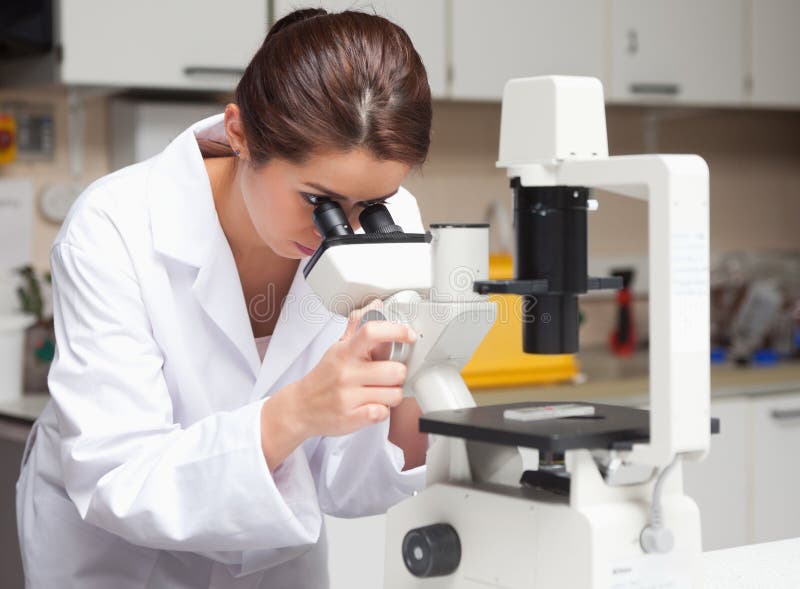 Female science student looking in a microscope stock photography