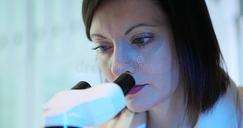 Female scientist, biologist, laboratory technician or doctor uses microscope in laboratory setting stock video