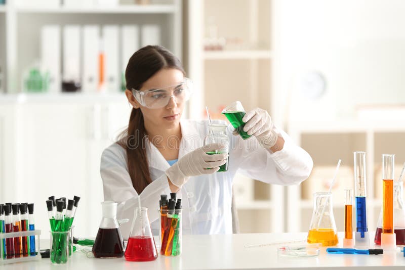 Female scientist dropping color sample into test flask in laboratory royalty free stock image