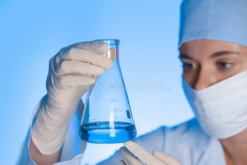 Female scientist holding test flask with sample on color background. royalty free stock photography