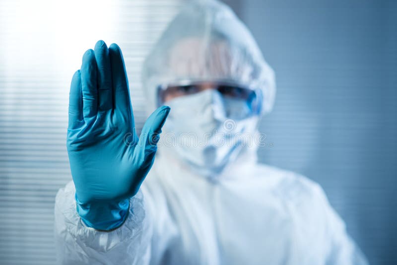 Female scientist in protective hazmat suit with hand raised