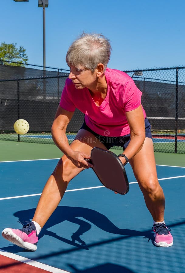 Female senior female player readies her paddle to volley the pickleball