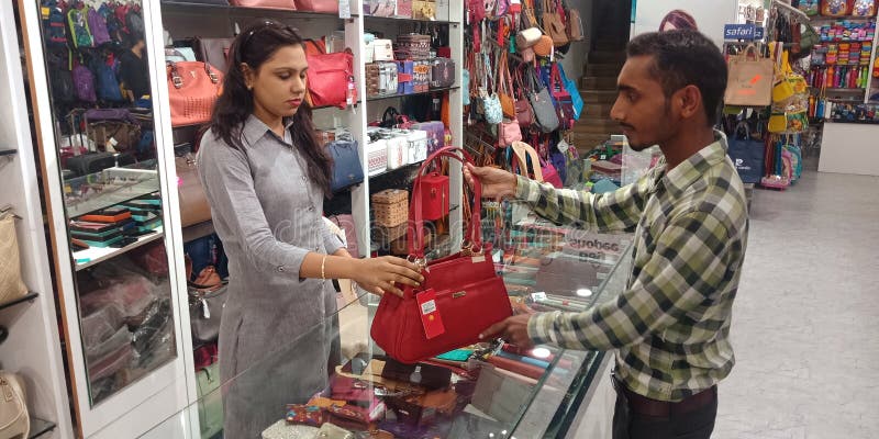 female shopkeeper showing hand purse to the male customer at bag store