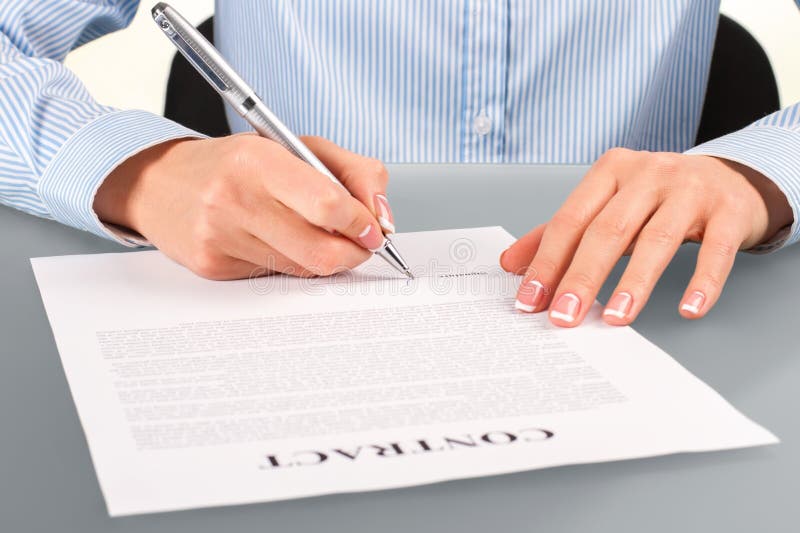 Female signing contract at desk.