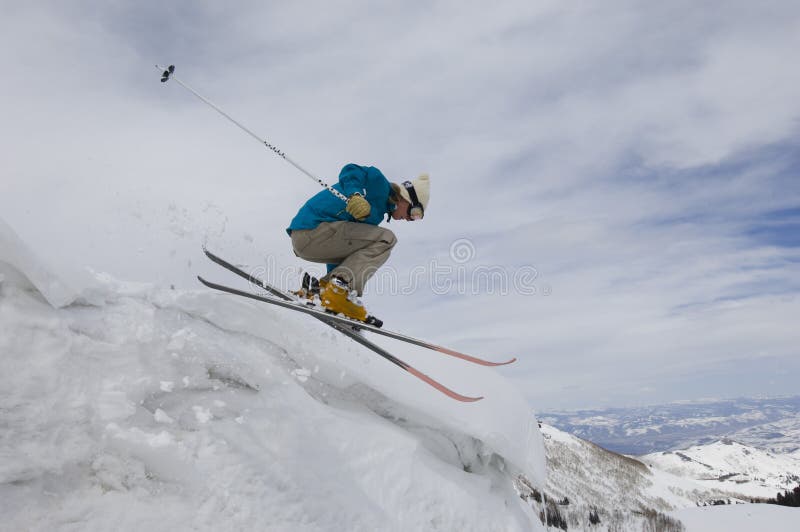 Female Skier Jumping Off Icy Overhang royalty free stock image