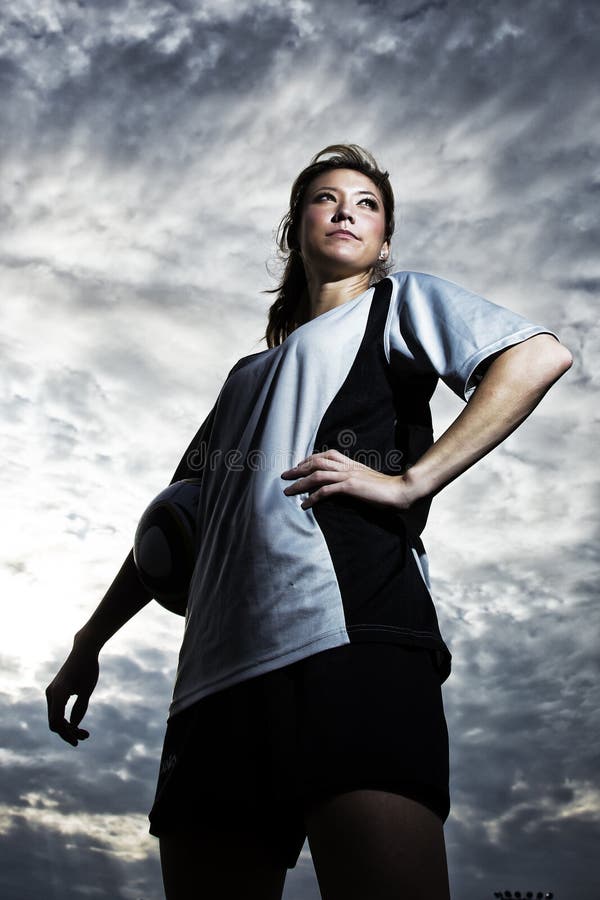 Eine junge weibliche Fußball-Spieler posiert vor einem dramatischen hintergrund.
