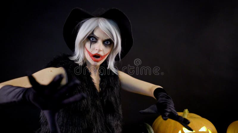 Female sorceress with gray hair scares, conjures, casts a spell. Scary beautiful girl witch celebrates halloween with