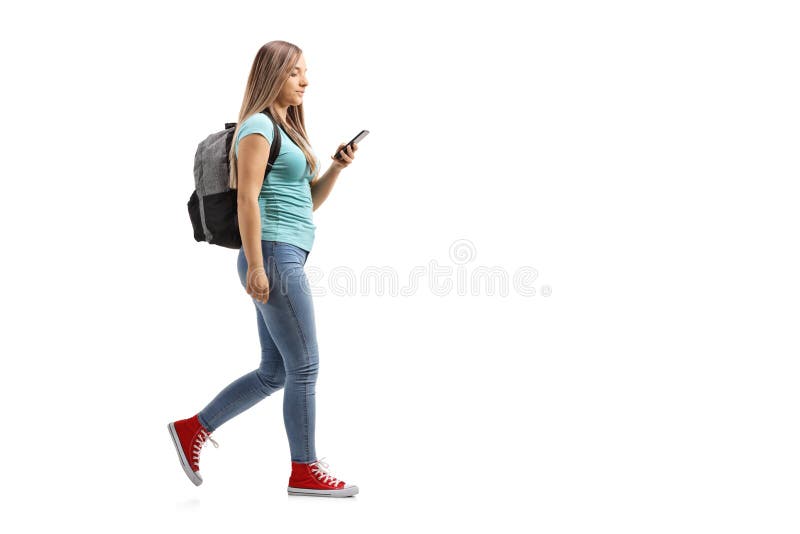 Female Student With Backpack Walking And Using A Mobile Phone Stock
