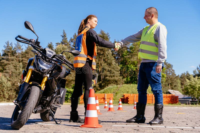 A Man and a Woman are Standing in Front of a Motorcycle Shaking Hands