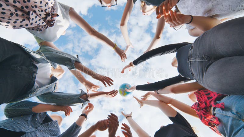 Female student girls standing in a circle toss the world globe up.