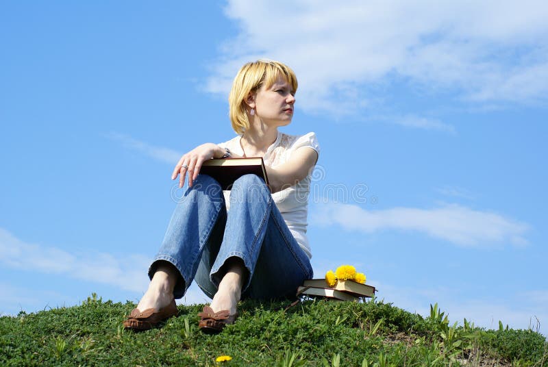 Female student outdoor on gren grass with books