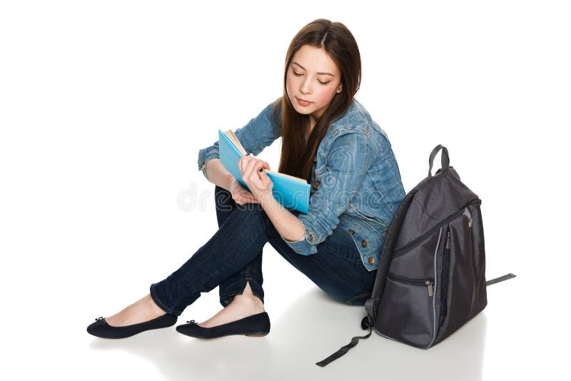 Female student sitting on floor with backpack reading a book