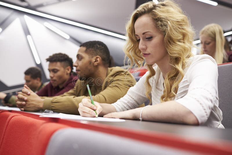 Female student taking notes in a university lecture theatre royalty free stock photo