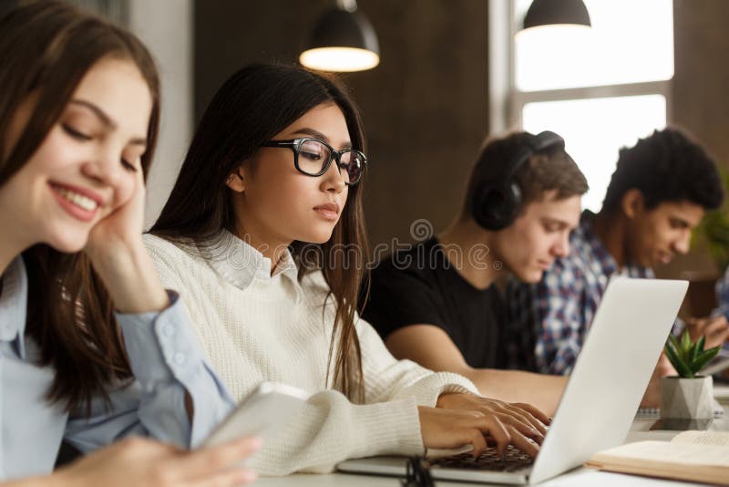 Female student typing on laptop, studying in library stock photo Female student typing on laptop, studying in library stock photo