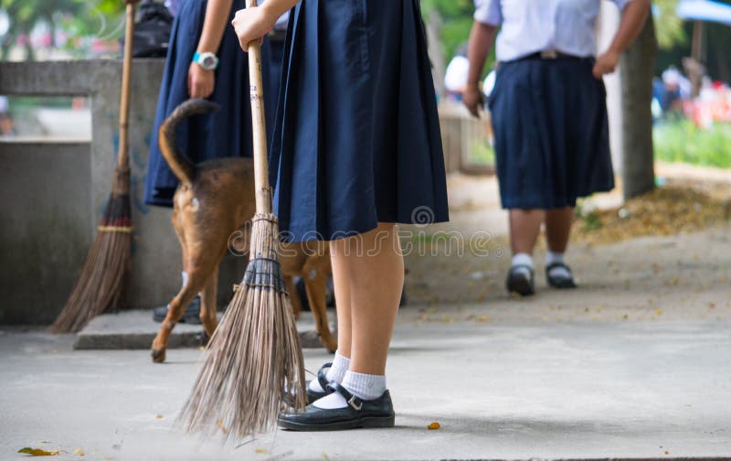 Female students help to sweep the concrete floor with a broom stock image Female students help to sweep the concrete floor with a broom stock image
