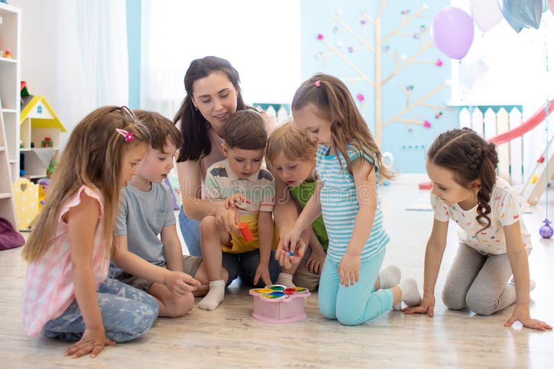 Female teacher teaching kids play toy in class room. Kindergarten preschool concept stock image Female teacher teaching kids play toy in class room. Kindergarten preschool concept stock image