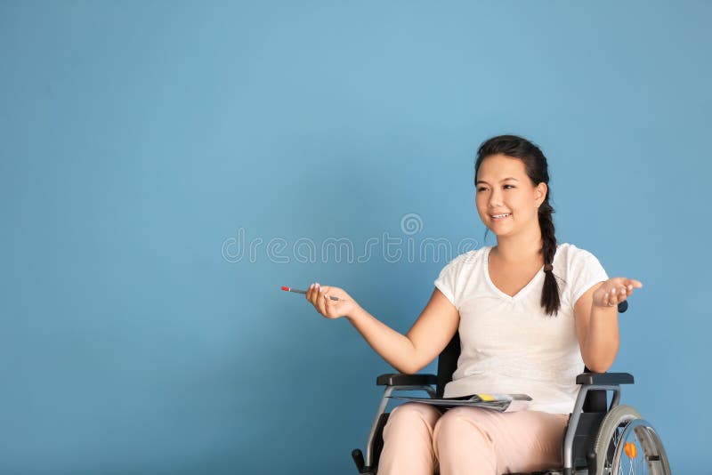 Female teacher in wheelchair on color background