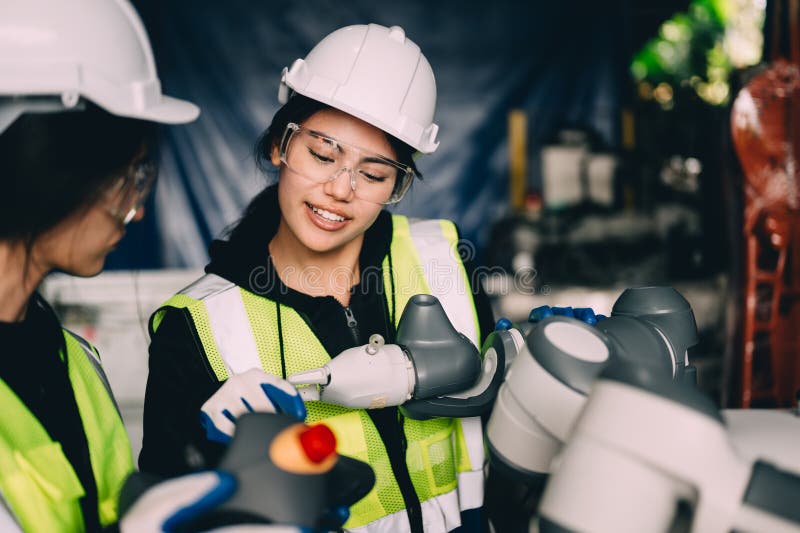 Female technician engineer using controller checking robotic machine. Female technician engineer using controller checking and operating automatic robotic machine at industrial factory, Worker working with robotic arms system in factory