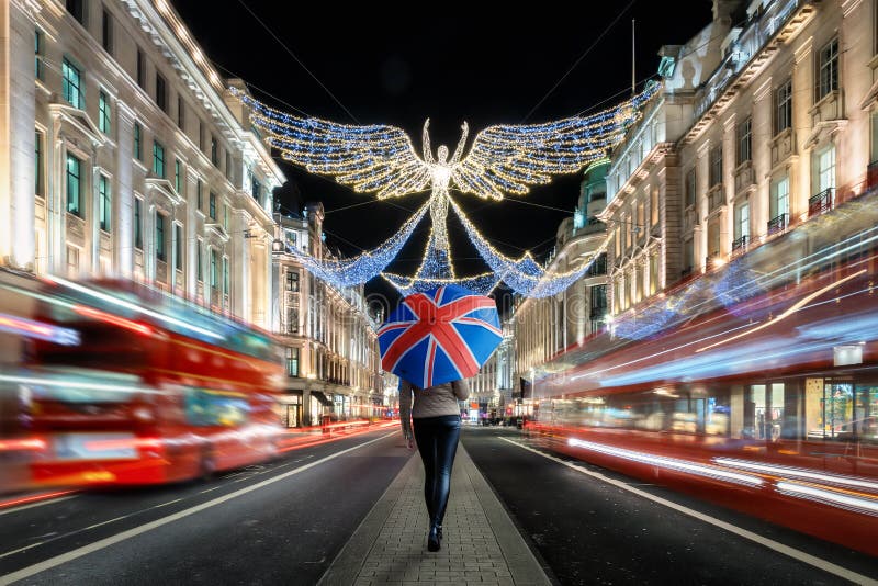 A female tourist holding an umbrella with a british flag on it explores the christmas decorated city center of London, United King stock images A female tourist holding an umbrella with a british flag on it explores the christmas decorated city center of London, United King stock images