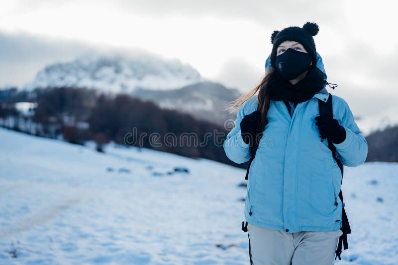 Female tourist wearing a protective mask in nature on mountain holiday vacation.Active vacation during the pandemic.Natural beauty