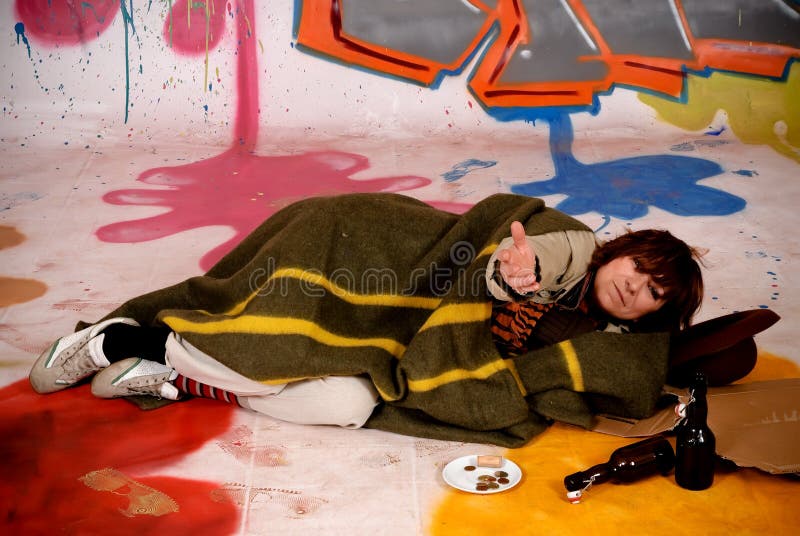 Female tramp, beggar in front of graffiti wall, urban setting. Studio shoot. Female tramp, beggar in front of graffiti wall, urban setting. Studio shoot.