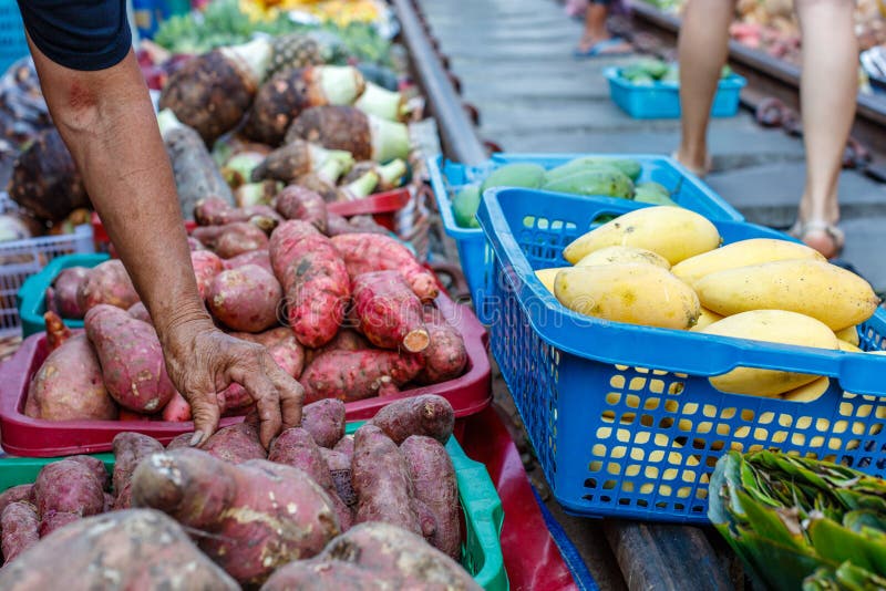Female vendor checking sweet potatoes at a famous Maeklong railway market , Samut Songkhram province, Thailand. stock photography Female vendor checking sweet potatoes at a famous Maeklong railway market , Samut Songkhram province, Thailand. stock photography