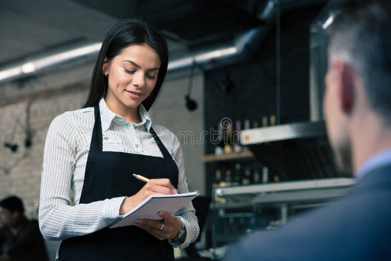 Female waiter in apron writing order