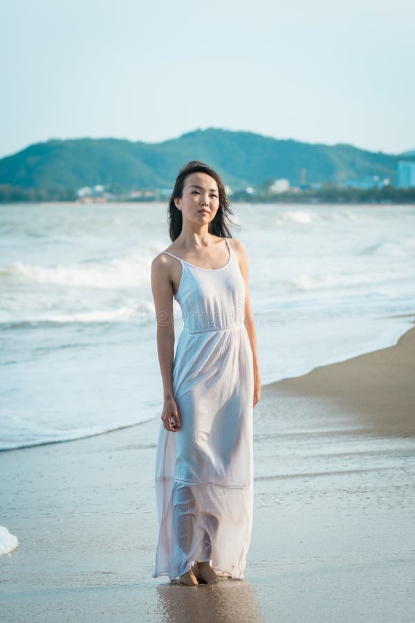 Female walking on beach in summer. Happy multiracial Asian girl going to sea.