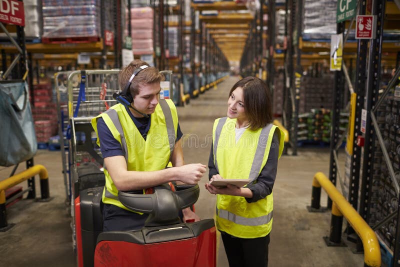 Female Warehouse Manager Instructing Man on Tow Tractor Stock Photo