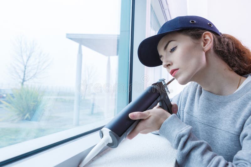 Female window installer sealing gaps with epoxy gun royalty free stock photo Female window installer sealing gaps with epoxy gun royalty free stock photo