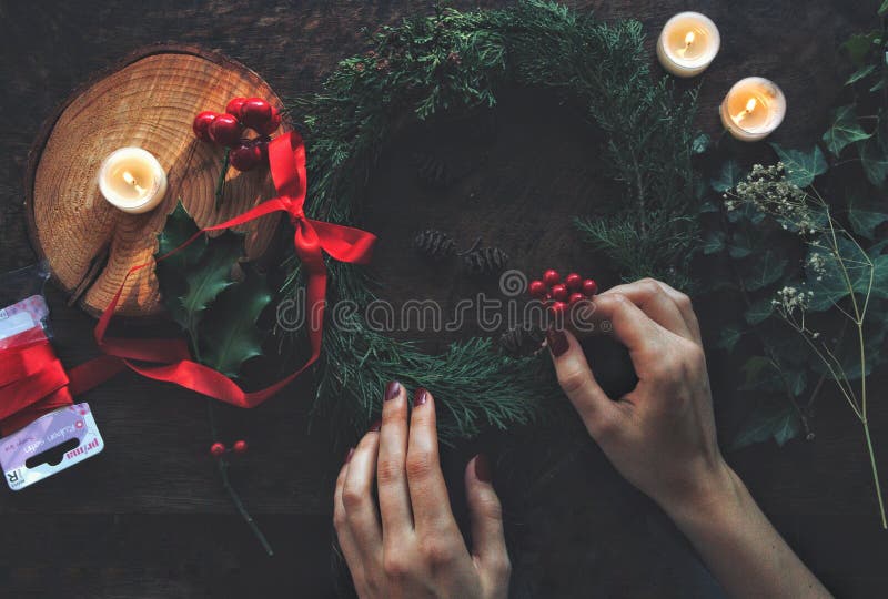 Female woman hands making DIY Yule winter solstice Christmas wreath from cedar evergreen tree branches.