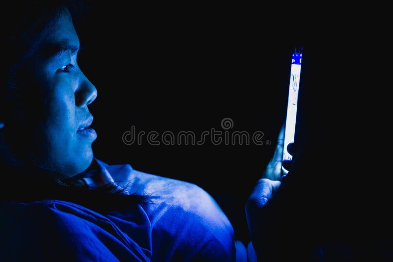 Femei ea a jucat telefonul inteligent în lumina întunecată și lumina albastră are un efect negativ asupra ochilor royalty free stock photography