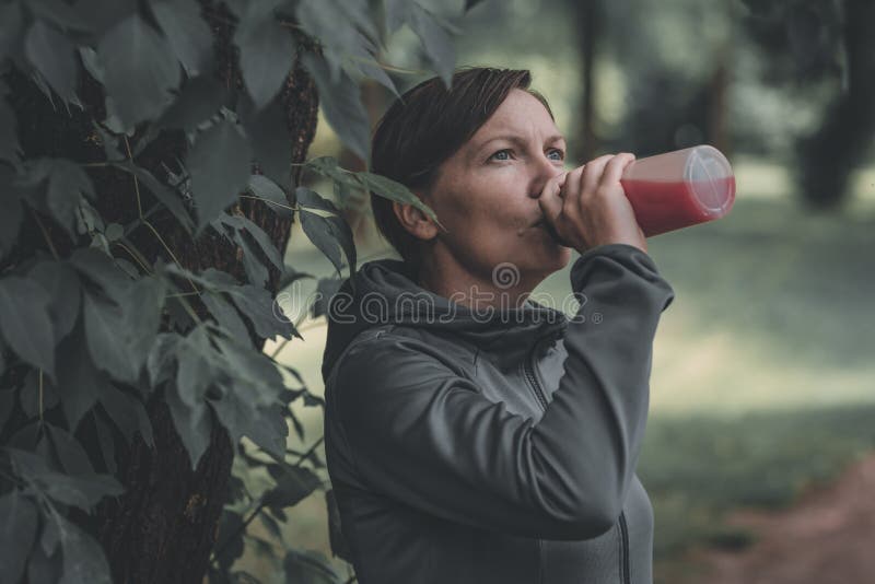 Femeie alergător băut suc de căpșuni reîmprospătat în parc royalty free stock photography
