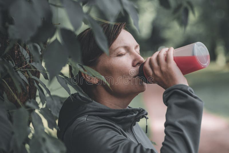 Femeie alergător băut suc de căpșuni reîmprospătat în parc royalty free stock images