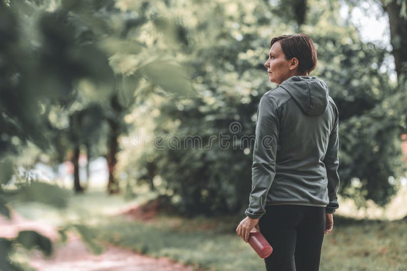 Femeie alergător care deține o sticlă de suc de căpșuni reîmprospătat în parc royalty free stock images