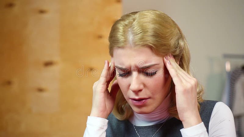 Femeie blondă cu dureri de cap la locul de muncă. stres și probleme stock footage