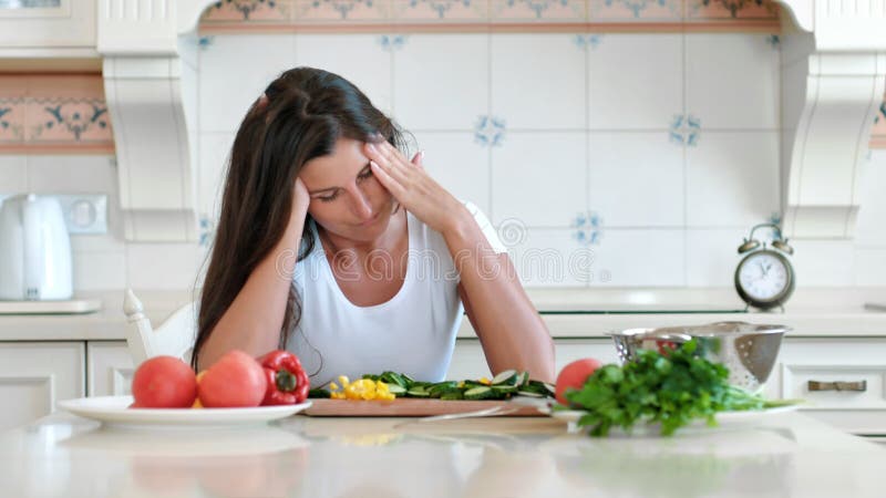 Femeie-casnică obosită portret, cu dureri de cap care ating capul făcând masaj circular în timp ce gătește stock footage