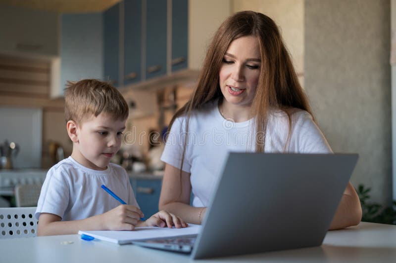 Femeie caucaziană ajută băiatul să învețe lecții. tutorele verifică temele copiilor. carantină individuală la domiciliu. . a stock photo
