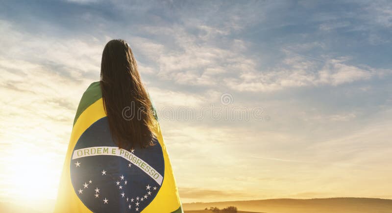 Femeie cu pavilion brazilian privind apusul royalty free stock image