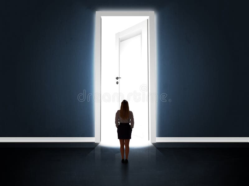 Femeie de afaceri care se uită la o ușă mare și strălucitoare deschisă stock photo