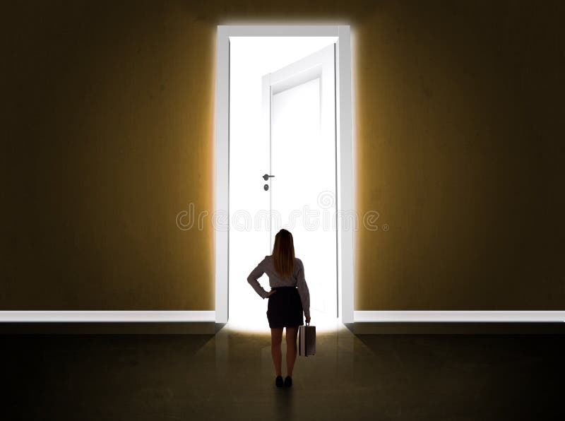 Femeie de afaceri care se uită la o ușă mare și strălucitoare deschisă royalty free stock photography
