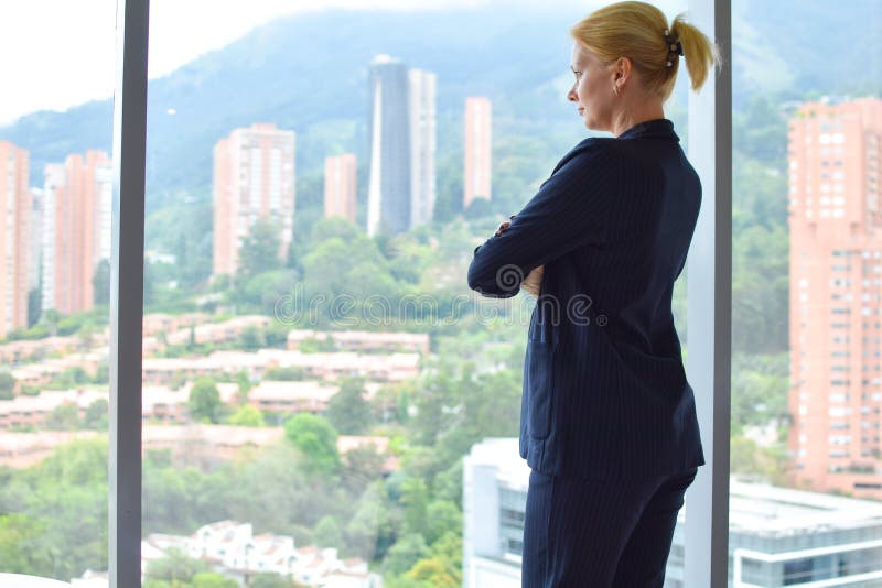 Femeie de afaceri stă lângă fereastră. bucurie feminină. tânăra fată fericită într-un costum de afaceri în cameră zâmbind stock photo