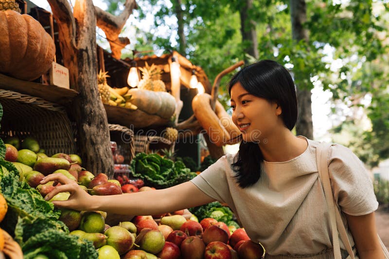 Femeie la o piață de fermieri cu fructe și legume ecologice. femeie asiatică la o piață locală în aer liber stock image