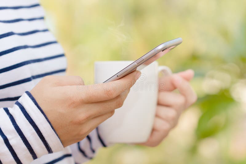 Femeie închisă folosind telefonul și cafeaua în dimineața stock photos