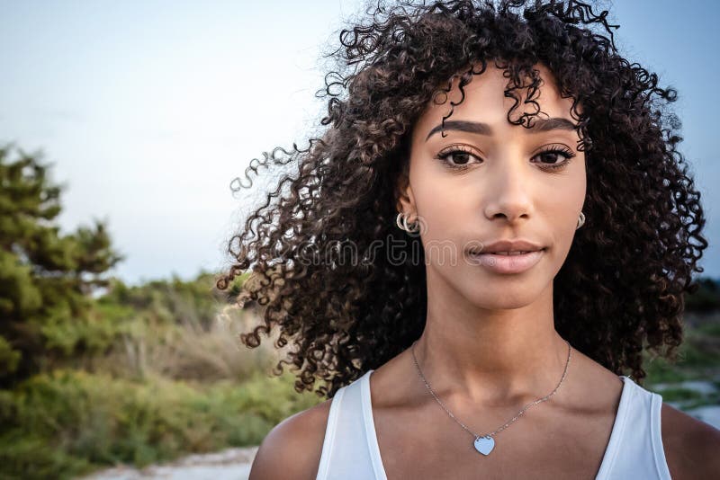 Feminilidade e beleza na natureza : retrato aproximado de uma linda jovem negra hispânica, de cabelo crespo encaracolado