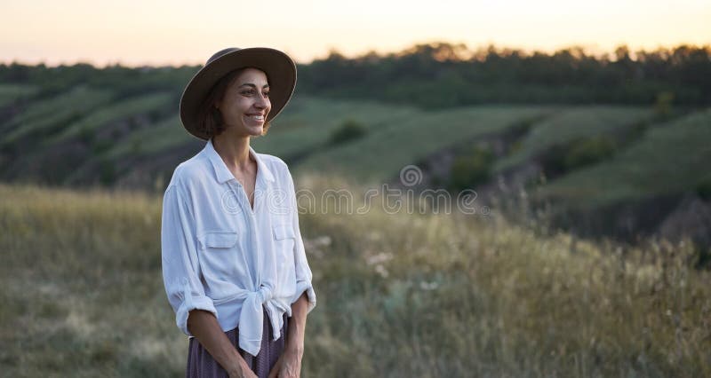 Femininity stylish lady in beautiful nature with serene hillside walking in meadow during sunset. Femininity stylish lady in beautiful nature with serene hillside walking in meadow during sunset