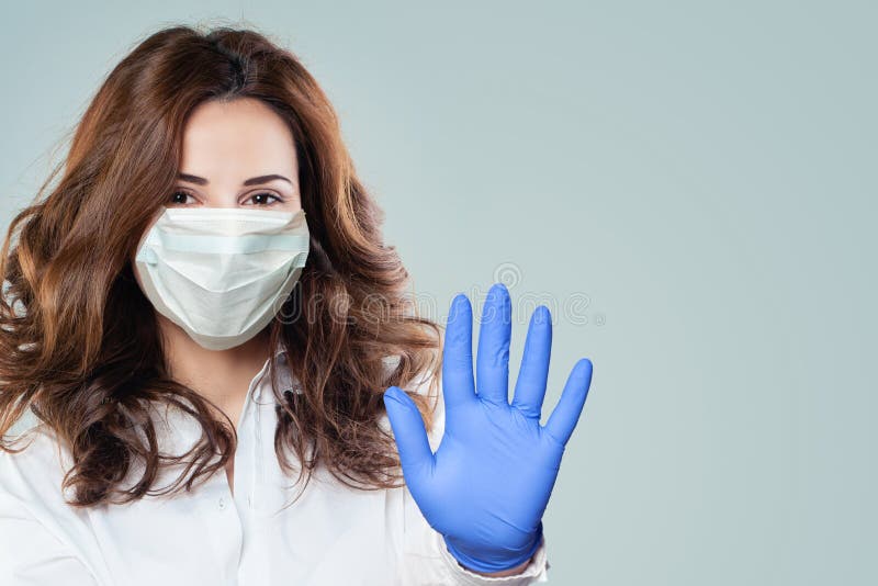 Happy smart doctor woman in a medical face mask showing stop pandemic gesture. Woman in safety mask and medical gloves. Flu epidemic and virus covid-19 protection concept. Happy smart doctor woman in a medical face mask showing stop pandemic gesture. Woman in safety mask and medical gloves. Flu epidemic and virus covid-19 protection concept